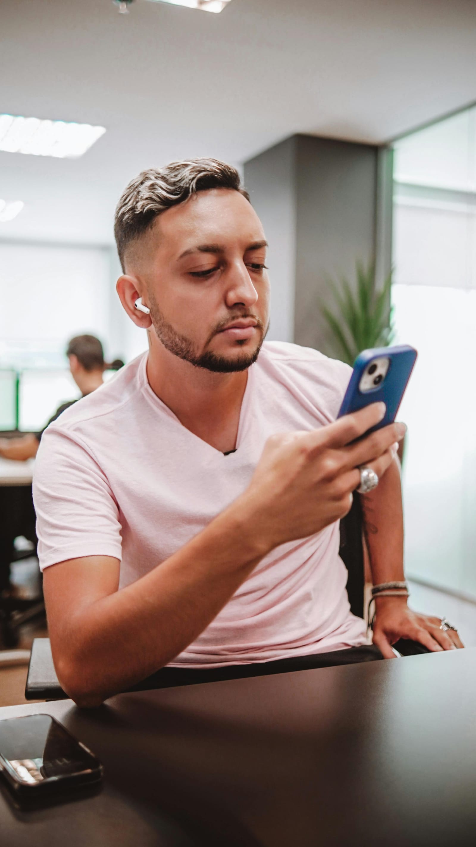 Jovem pensativo olhando o celular, decidindo se vale a pena se inscrever no curso gratuito de tecnologia